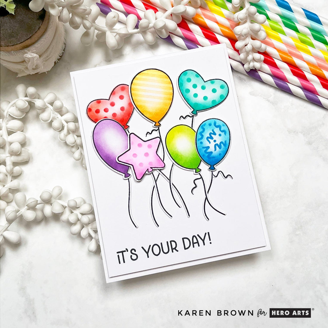A handmade card featuring 7 stamped , ink blended and stenciled floating, dancing balloons.